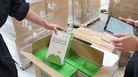 Person hält eine Packung von Schutzmasken Person hält eine Packung von Schutzmasken