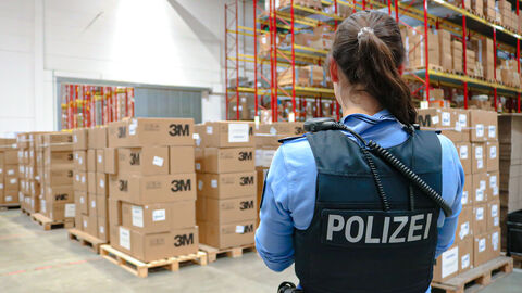 Polizistin steht vor einem Lager