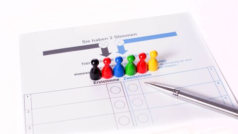 Stimmzettel mit bunten Männchen und ein Stift