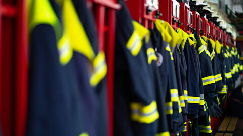 Feuerwehranzüge und Helme in einer Feuerwache Feuerwehranzüge und Helme in einer Feuerwache