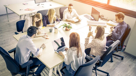 Kollegen beraten sich an einem Großen Tisch im Büro