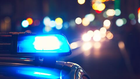 Polizeiauto mit Blaulicht auf einer dunklen Straße  Polizeiauto mit Blaulicht auf einer dunklen Straße
