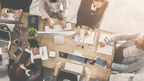 Kollegen beraten sich an einem großen Tisch im Büro