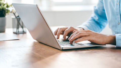 Hände einer Person über der Laptoptastatur während der Arbeit