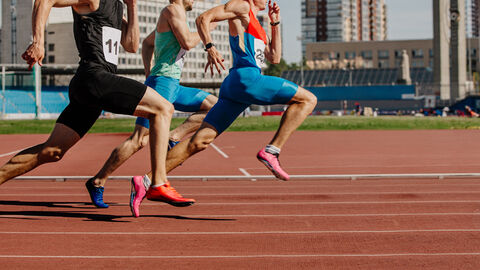 Männer-Sprinter laufen im Leichtathletik-Wettkampf auf der Bahn Männer-Sprinter laufen im Leichtathletik-Wettkampf auf der Bahn