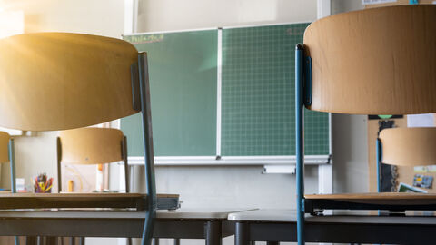 Leeres Klassenzimmer mit Stühlen auf den Tischen und leere grüne Tafel Leeres Klassenzimmer mit Stühlen auf den Tischen und leere grüne Tafel