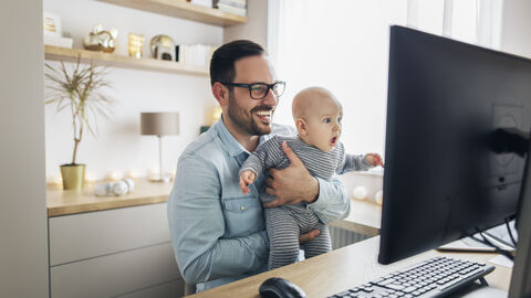 Vater sitzt mit Baby vor dem Laptop und lachen Vater sitzt mit Baby vor dem Laptop und lachen