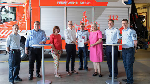 Innenminister Beuth mit Beteiligten der Feuerwehren vor einem Feuerwehrauto bei der Bescheidübergabe