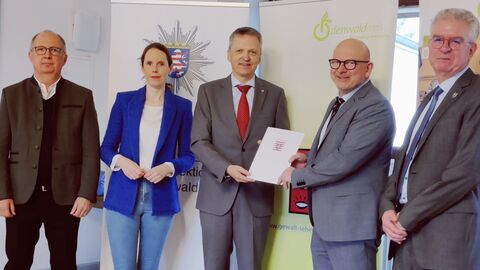 v. l. nach r. Bürgermeister der Stadt Erbach Dr. Peter Traut, Landtagsabgeordnete Sandra Funken, Innenstaatssekretär Martin Rößler, Landrat des Odenwaldkreises Frank Matiaske, Leiter der regionalen Kriminalinspektion Odenwaldkreis Ralf Levita. Alle stehen nebeneinander vor einem Aufsteller. Staatssekretär Rößler übergibt die Urkunde an den Landrat.