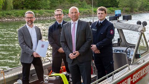 Bürgermeister Thorsten Siehr, Herr Neumann und Herr Benz von der Feuerwehr Ginsheim-Gustavsburg mit Innenminister Roman Poseck posieren im neuen Mehrzweckboot
