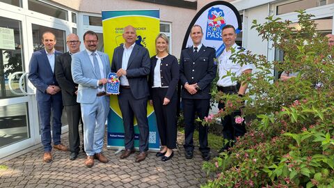 Innenminister Poseck gemeinsam mit Akteuren der Gemeinde vor einem Gebäude. 