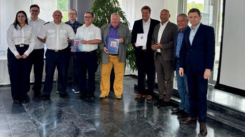 Innenminister Poseck mit weiteren Personen bei der Bescheidübergabe. Sie stehen in einem Raum zum Gruppenfoto aufgestellt.