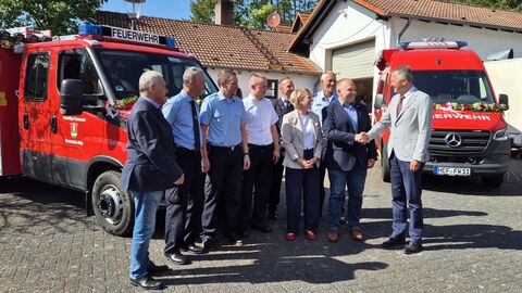 Gemeindefeuerwehrtag der Freiwilligen Feuerwehr Neuenstein Staatssekretär Martin Rößler steht mit Gemeindemitgliedern vor dem neuen Löschfahrzeug für die Freiwillige Feuerwehr Neuenstein