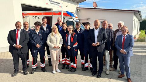 Das Team der DRK sowie Innenminister Poseck und Gesundheitsministerin Stolz stehen vor der Rettungswache Flörsheim-Wicker.