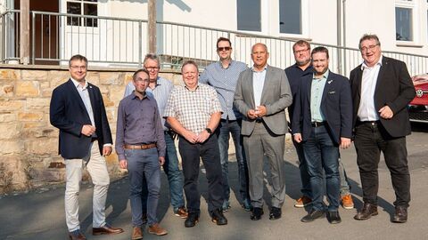 Innenminister Roman Poseck steht mit weiteren Personen vor einem Gebäude.