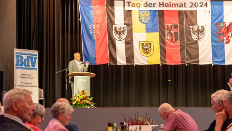 Innenminister Poseck hält Rede auf Bühne. Im Hintergrund sieht man verschiedene Flaggen.