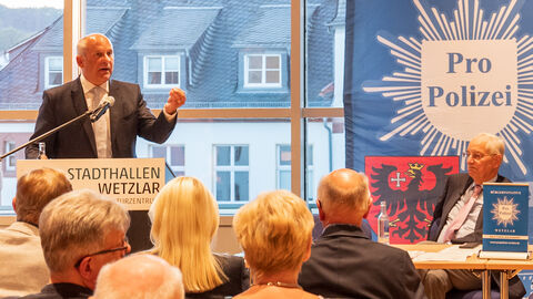 Innenminister Roman Poseck hält Rede auf Bühne. Im Hintergrund steht "Pro Polizei".