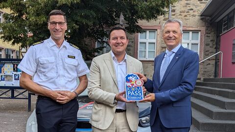 Innenstaatssekretär übergibt dem Bürgermeister der Stadt HOfheim am Taunus das Sicherheitssiegel. Polizeipräsident Felix Paschek steht daneben.