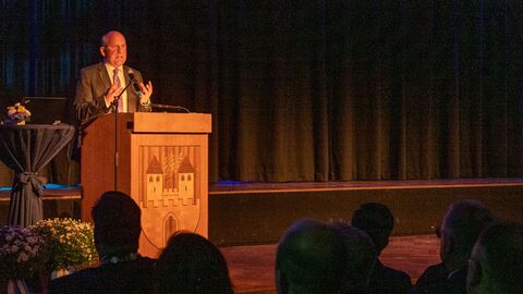 Der Innenminister steht am Podest und hält eine Rede vor Publikum.