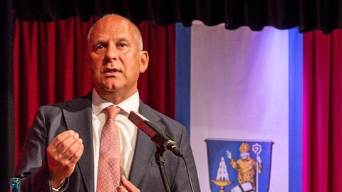 Innenminister Roman Poseck steht an einem Pult und hält eine Rede zum Publikum.