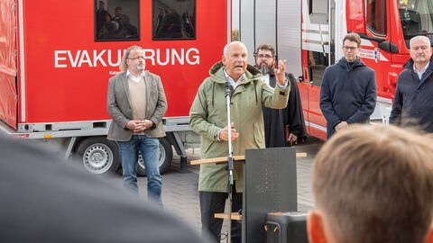 Roman Poseck steht vor einem Fahrzeug und hält eine Rede vor Publikum.