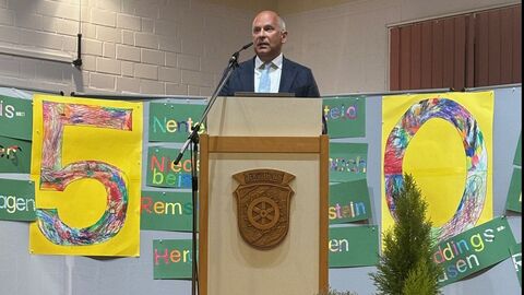 50 Jahre Knüllwald Kommunalminister Roman Poseck an Rednerpult. Im Hintergrund sieht man eine gemalte 50.