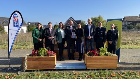 8 Personen stehen nebeneinander. Innenminister Poseck und Bürgermeisterin Lena Herget halten das KOMPASS-Begrüßungsschild in der Hand.