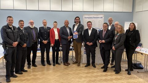 Männer und Frauen stehen nebeneinander. Ein Mann hält das Sicherheitssiegel in der Hand.