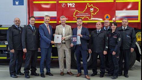 Männer und Frauen stehen vor einem Feuerwehrauto.