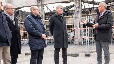 Innenminister Poseck spricht vor 5 Männern, die gespannt zuhören.