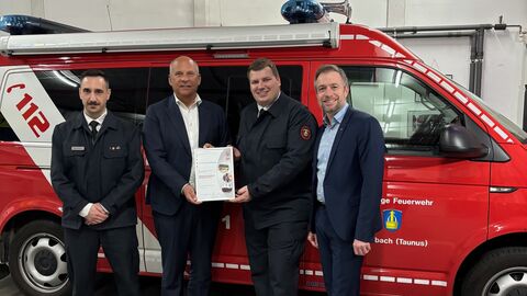 Vier Männer stehen vor einem Feuerwehrauto