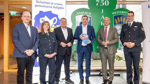 Fünf Männer und eine Frau stehen nebeneinander. Ein Mann hält ein Siegel in der Hand.