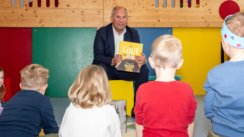 Mann zeigt Kindern ein Buch.