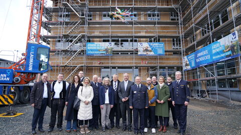 Menschen stehen vor frisch gebautem Gebäude.