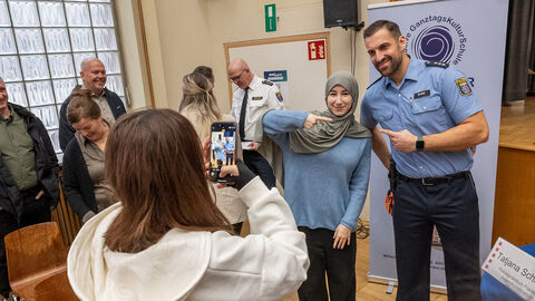 Cops im Dialog Schülerin posiert mit Polizisten. Eine andere Schülerin macht ein Bild mit ihrem Handy.