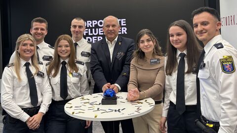 Innenminister Poseck steht mit sechs Polizistinnen und Polizisten in Ausbildung um einen Stehtisch herum.