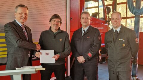 Vier Männer stehen vor Feuerwehr-Auto