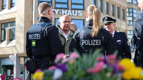 Eine Gruppe Polizistinnen und Polizisten stehen gemeinsam mit Innenminister Poseck in der Stadt und sprechen.