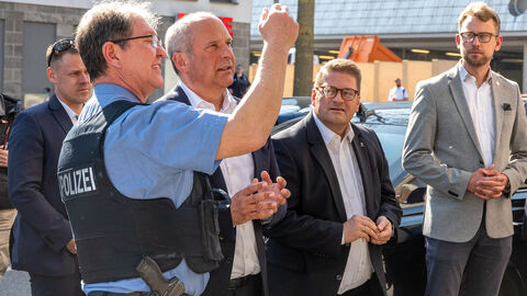 Ein Polizist zeigt Innenminister Poseck etwas in der Stadt.
