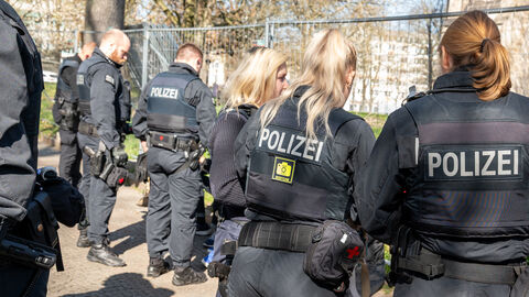Polizistinnen und Polizisten stehen an einem Zaun.