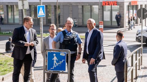 An einem Fußweg steht Innenminister Poseck mit einem Polizisten.