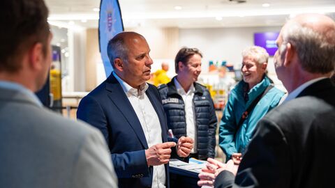 Innenminister Poseck steht an einem Messestand und spricht mit umherstehenden Personen.