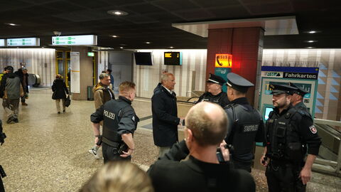 In einer U-Bahn-Station steht Innenminister Poseck mit Polizisten zusammen.