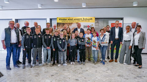 Eine Gruppe steht zum Gruppenfoto aufgestellt zusammen.