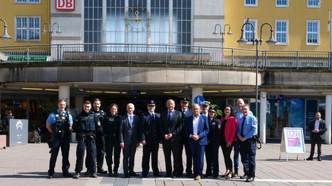 Innenminister Poseck mit einer Gruppe von Polizisten und Polizistinnen vor einem Bahnhofsgebäude.