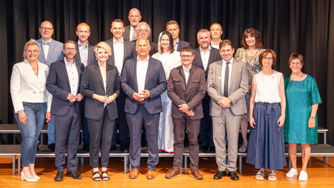 Kommunalminister Roman Poseck mit einer Gruppe von Menschen vor einem neutralen Hintergrund
