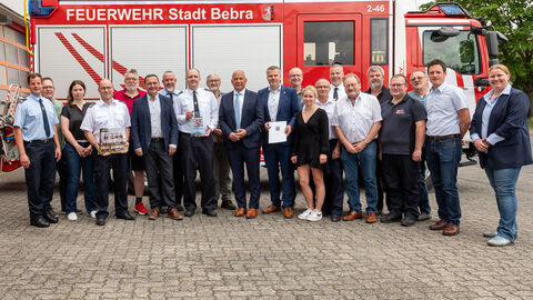 Innenminister Roman Poseck mit einer größeren Gruppe von Menschen vor einem Feuerwehrwagen.