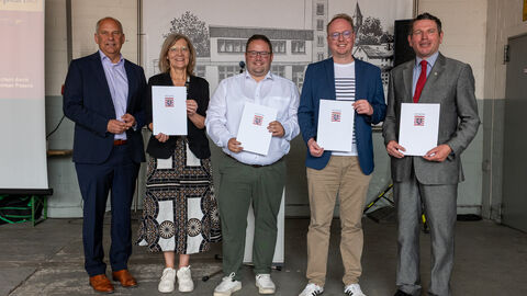 Innenminister Poseck steht mit weiteren Personen zusammen, die Zuwendungsbescheide in Händen halten.