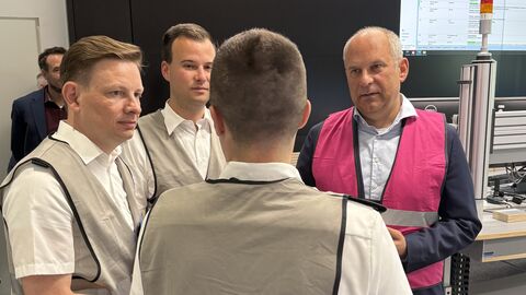 Roman Poseck trägt eine pinke Warnweste und spricht mit drei Männern, die jeweils graue Warnwesten tragen.