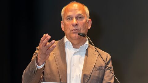 Mann hält Rede auf Bühne.